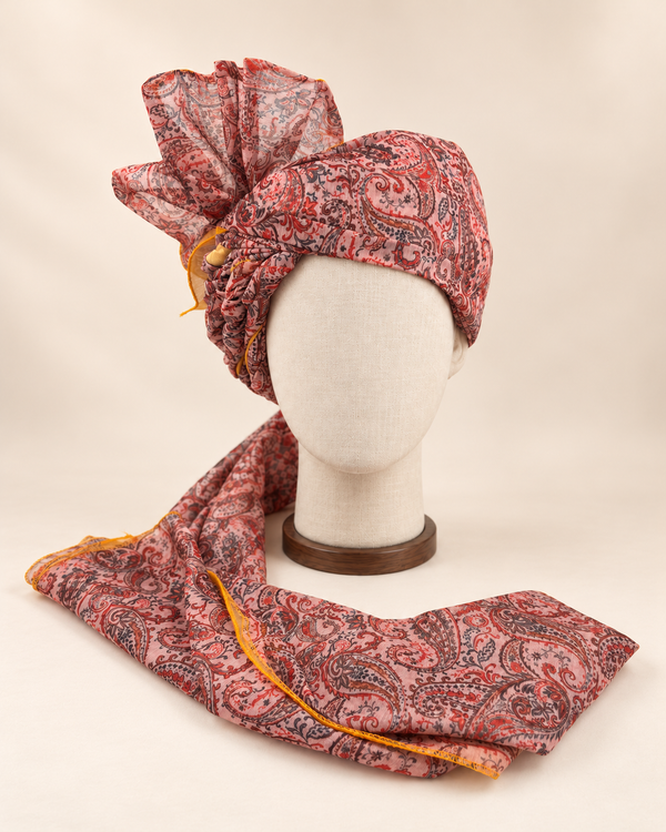 Front view of blush pink paisley Barati Safa with red and charcoal motifs and mustard yellow edging