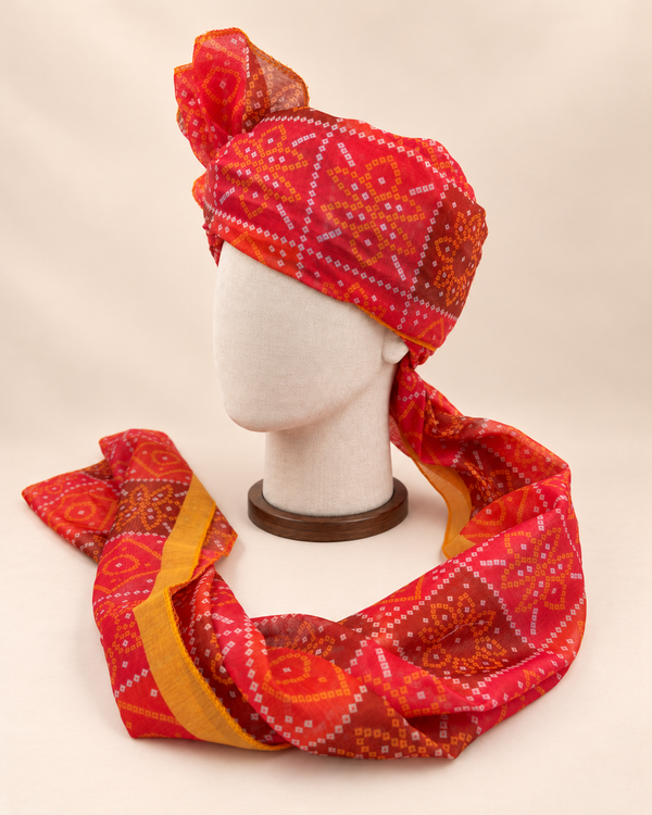 Left side view of red diamond bandhani print barati safa showing the smooth wrap and long patterned tail